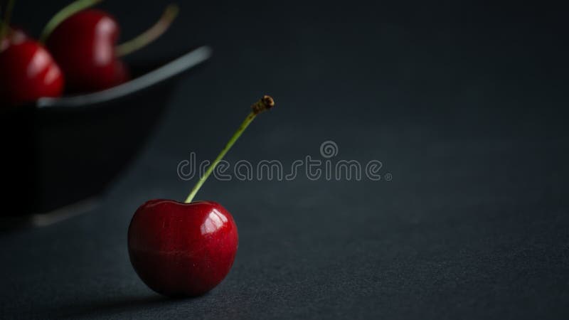 Close up view  fresh fruit sweet ripe cherry in dark light and black background with water droplets low key still life. Close up view  fresh fruit sweet ripe cherry in dark light and black background with water droplets low key still life