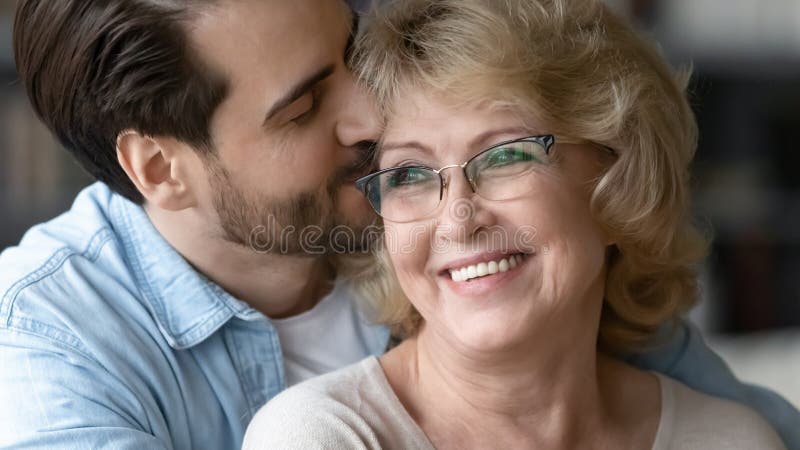 κοντινό ενήλικο παιδί φιλάει όμορφη ώριμη μητέρα φορώντας γυαλιά στοκ εικόνες με δικαίωμα ελεύθερης χρήσης