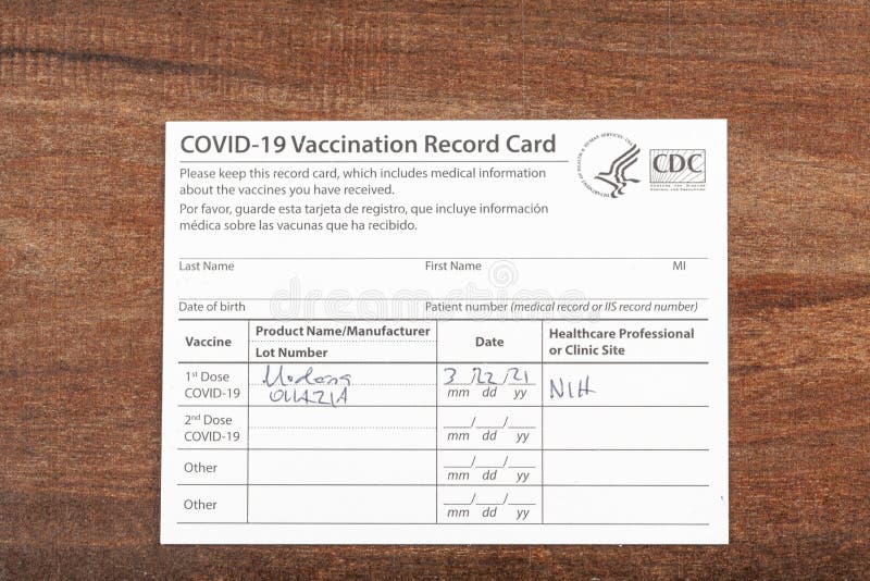Bethesda, MD, USA 03-22-2021: a COVID 19 vaccination record card on a wooden desk. The card details the date, type and the dose number of administred vaccine and given to every person for record. Bethesda, MD, USA 03-22-2021: a COVID 19 vaccination record card on a wooden desk. The card details the date, type and the dose number of administred vaccine and given to every person for record