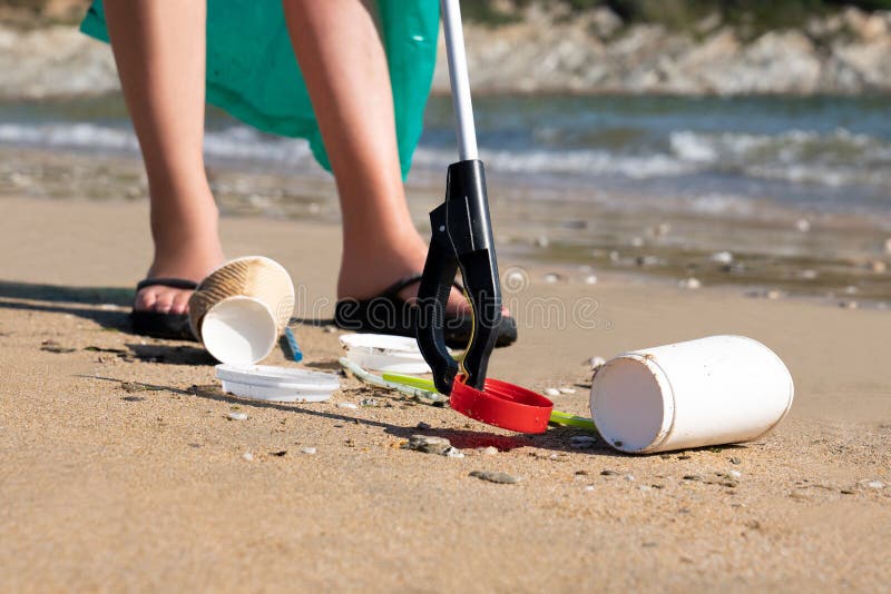 Person Collecting Plastic Waste From Polluted Beach Using Litter Picker. Person Collecting Plastic Waste From Polluted Beach Using Litter Picker