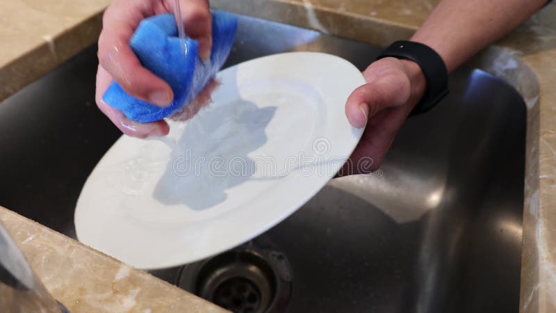 κοντινό πλύνετε τα αρσενικά χέρια πλένοντας ένα πιάτο με ένα σφουγγάρι στο νεροχύτη απόθεμα βίντεο