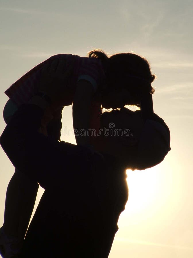 Sillouette of father holding daughter in the air ready to kiss. Sillouette of father holding daughter in the air ready to kiss