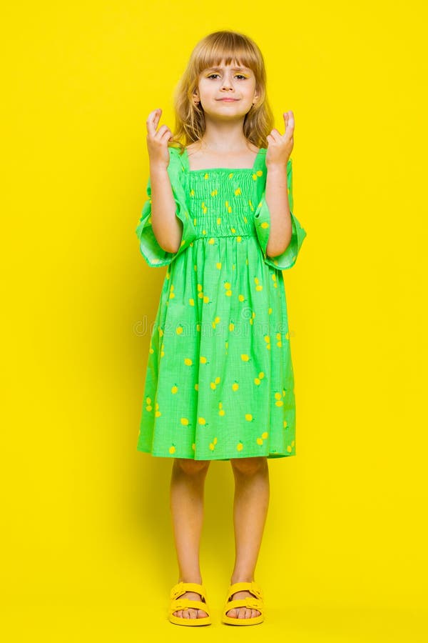 School girl crossed fingers looking at camera asking for good luck news, wishing good exam results dreaming about win victory in game play. Preteen child kid isolated on yellow background. Vertical. School girl crossed fingers looking at camera asking for good luck news, wishing good exam results dreaming about win victory in game play. Preteen child kid isolated on yellow background. Vertical