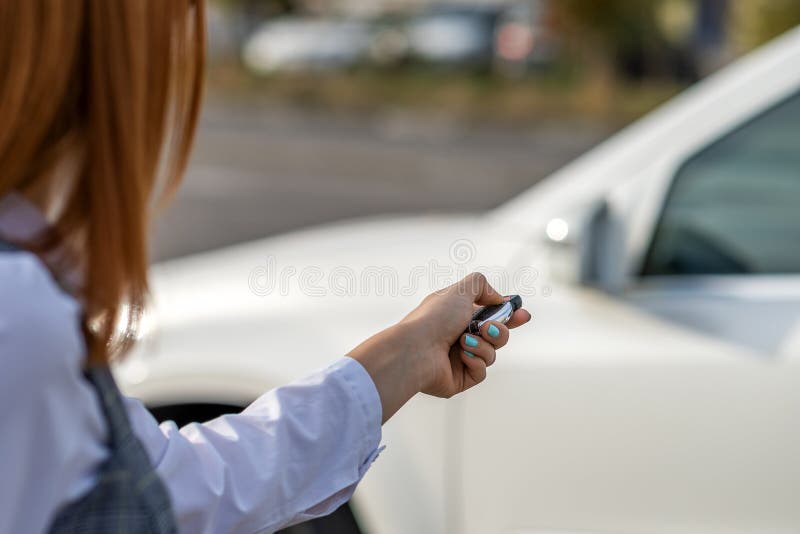 κορίτσι με κόκκινη κεφαλή ξεκλείδωσε ένα αυτοκίνητο με ασύρματο κλειδί στοκ φωτογραφία