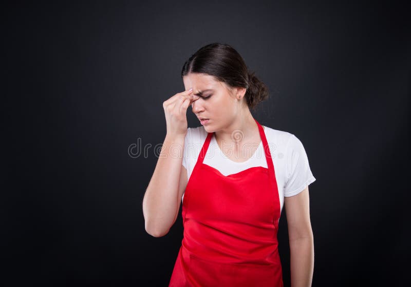 Supermarket seller girl with apron looking tired and stressed at her job. Supermarket seller girl with apron looking tired and stressed at her job