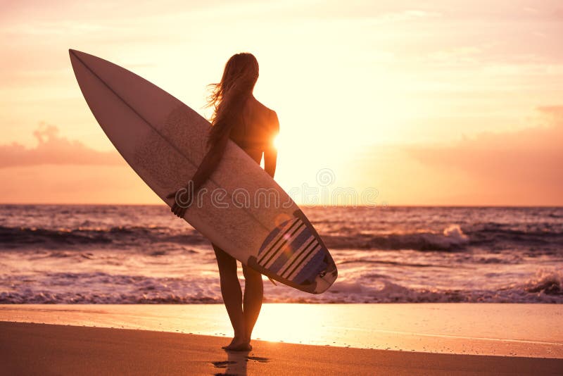 Κορίτσι σκιαγραφιών surfer στην παραλία στο ηλιοβασίλεμα στοκ φωτογραφία