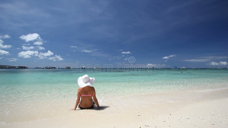 Κορίτσι στη χαλάρωση καπέλων ήλιων στην τροπική παραλία
