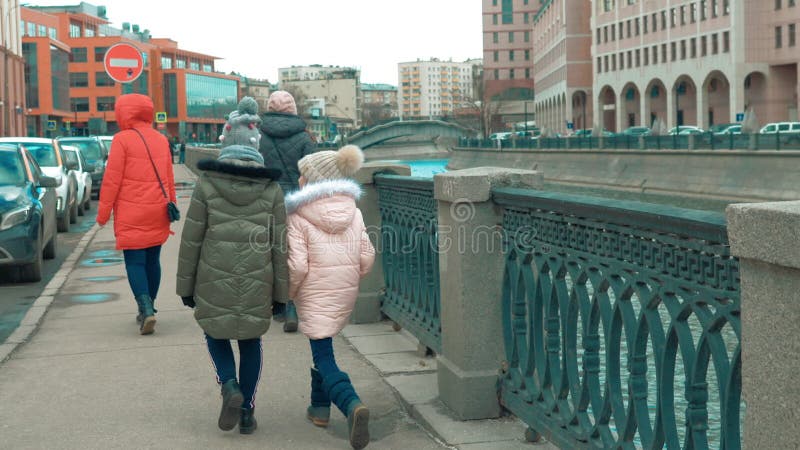 Κορίτσια με τα moms που περπατούν στο ανάχωμα πόλεων στο αστικό υπόβαθρο αρχιτεκτονικής