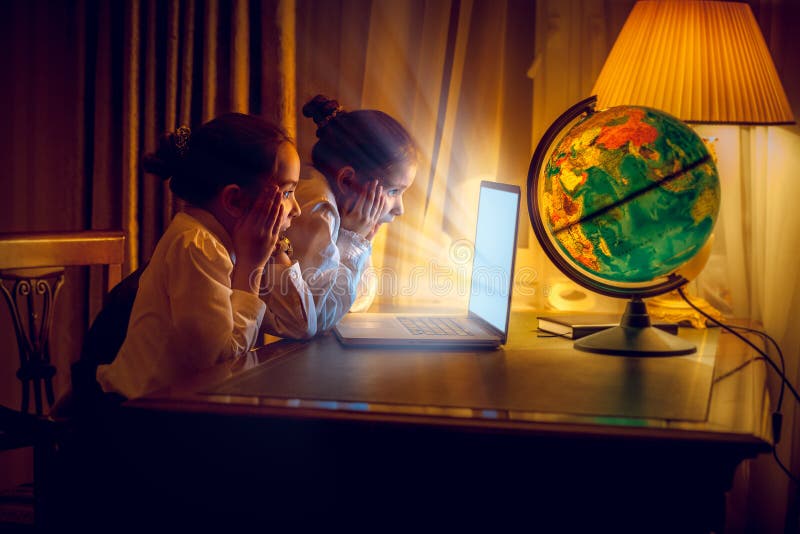 Κορίτσια που εξετάζουν με το amazement το lap-top τη νύχτα στοκ φωτογραφία με δικαίωμα ελεύθερης χρήσης