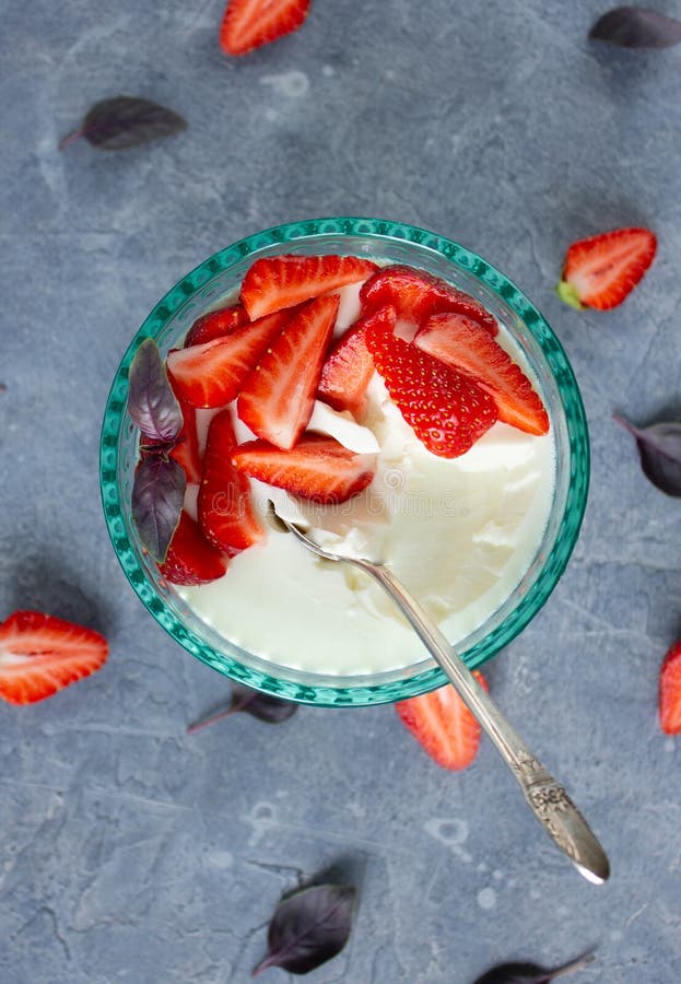 κορυφαία θέα στο panna cotta σε γυάλα με τυρκουάζ με φέτες φρέσκων φύλλων φράουλας βασιλικού και ένα ασημένιο κουτάλι σε σκυρόδεμα στοκ φωτογραφία με δικαίωμα ελεύθερης χρήσης