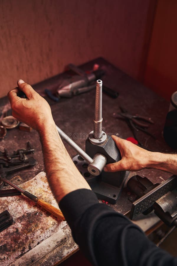 Craftsman putting ring on mandrel while spinning the lever on machine to stretch its size. Craftsman putting ring on mandrel while spinning the lever on machine to stretch its size