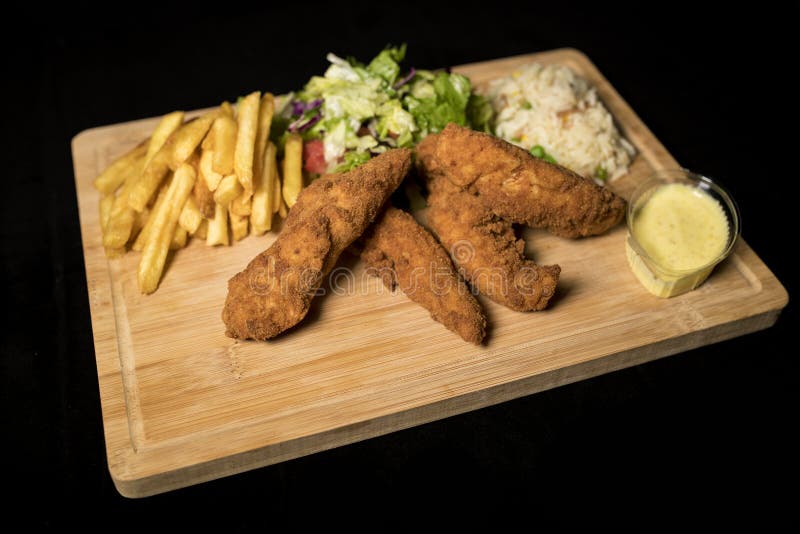 Κοτόπουλο Goujons που εξυπηρετείται με το ρύζι, τη σαλάτα και τις τηγανιτές πατάτες στο ξύλο στοκ φωτογραφία με δικαίωμα ελεύθερης χρήσης Κοτόπουλο Goujons που εξυπηρετείται με το ρύζι, τη σαλάτα και τις τηγανιτές πατάτες στο ξύλο στοκ φωτογραφία με δικαίωμα ελεύθερης χρήσης