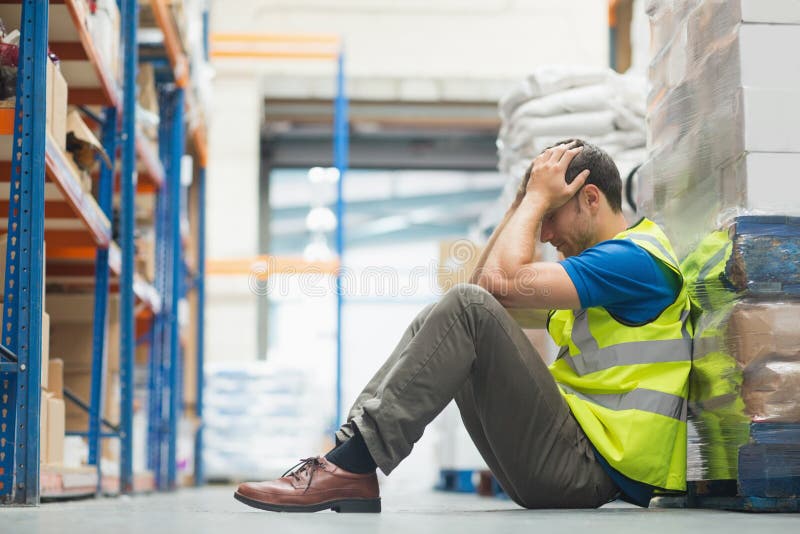 Tired man sitting on the couch with a headache in warehouse. Tired man sitting on the couch with a headache in warehouse