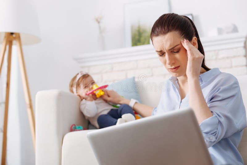 Strong pain. Ambitious but tired young women being exhausted from a great amount of work and need paying attention to her little child. Strong pain. Ambitious but tired young women being exhausted from a great amount of work and need paying attention to her little child