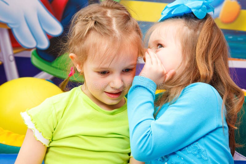 Preschool girl telling her friend some gossips. Preschool girl telling her friend some gossips