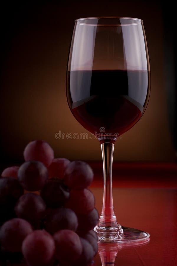 A wineglass and bunch of grapes on the table. A wineglass and bunch of grapes on the table