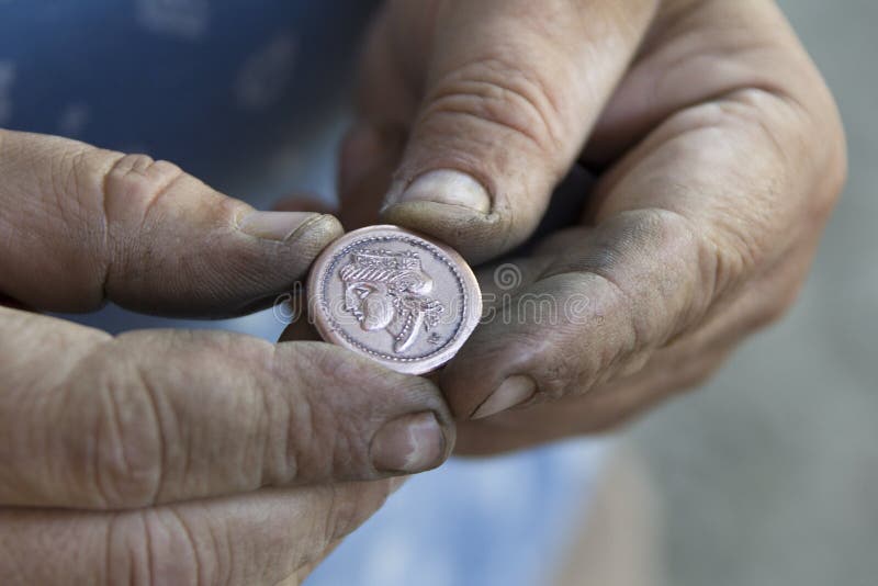 Κρατείστε τα χέρια σας το αρχαίο νόμισμα στοκ εικόνα με δικαίωμα ελεύθερης χρήσης