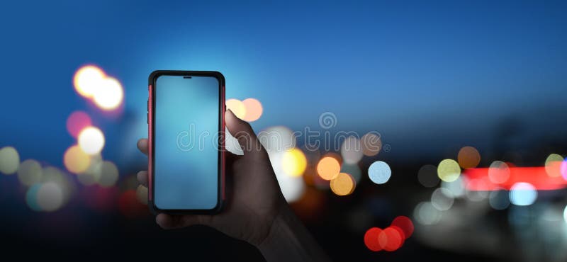 κρατώντας το smartphone τη νύχτα γεμάτο φώτα στοκ εικόνες