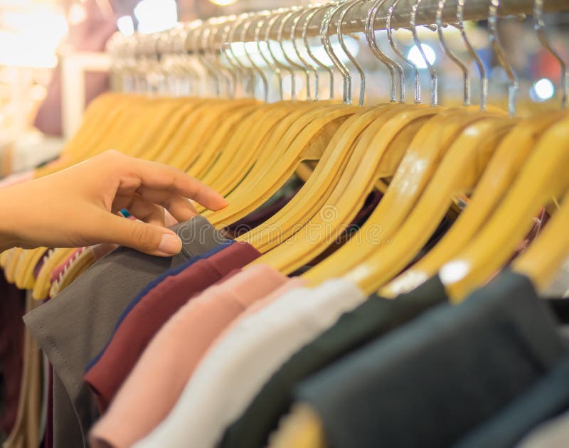 Wooden Clothes on Hanger with Woman`s Hand Choosing The Boutique Shirt at The Modern Shop. Wooden Clothes on Hanger with Woman`s Hand Choosing The Boutique Shirt at The Modern Shop