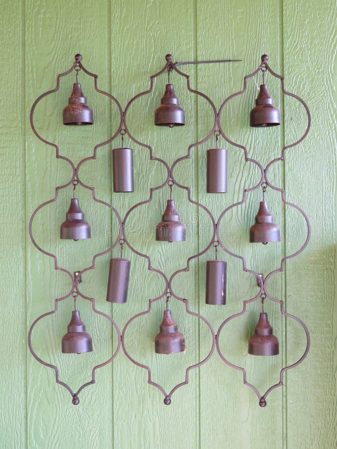 Hanging brass chimes in lantern pattern on green wood wall. Hanging brass chimes in lantern pattern on green wood wall