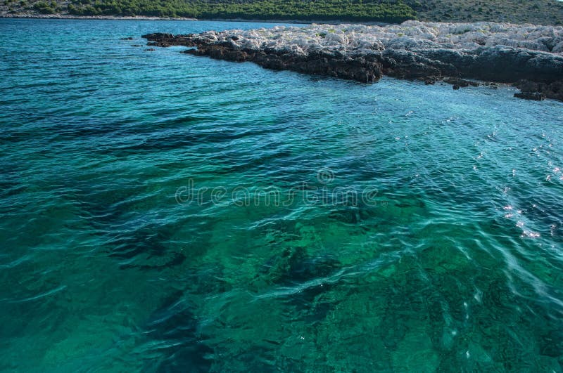 Κυματισμένη επιφάνεια του κρυστάλλου - σαφές, διαφανές θαλάσσιο νερό και λεπτομέρεια του δύσκολου νησακιού στοκ φωτογραφίες με δικαίωμα ελεύθερης χρήσης Κυματισμένη επιφάνεια του κρυστάλλου - σαφές, διαφανές θαλάσσιο νερό και λεπτομέρεια του δύσκολου νησακιού στοκ φωτογραφίες με δικαίωμα ελεύθερης χρήσης