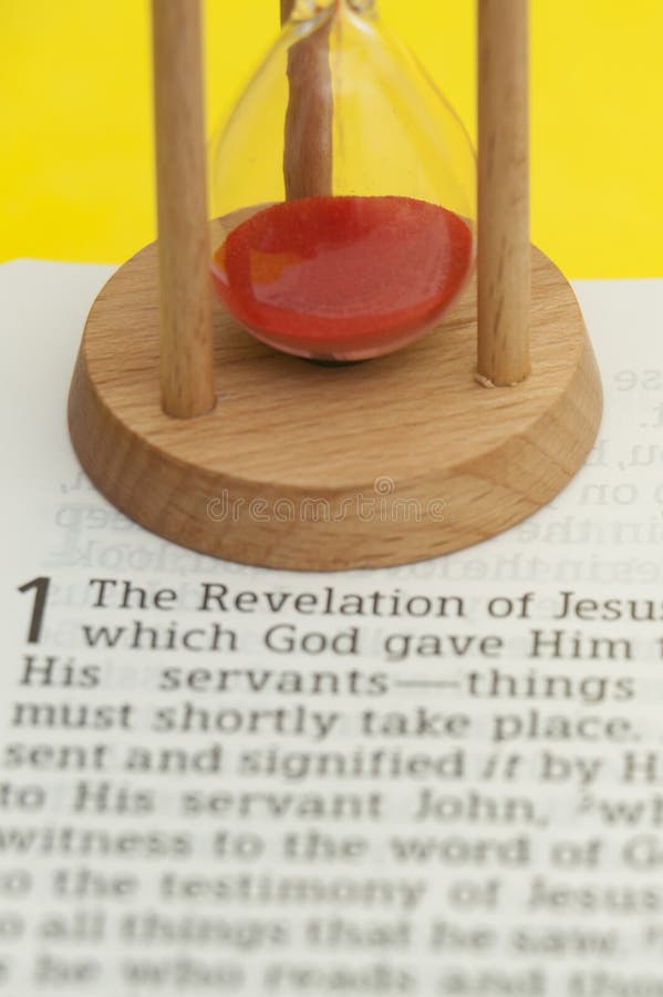Red sand hourglass on top of Holy Bible opened in Revelation of Jesus Christ Chapter 1. Red sand hourglass on top of Holy Bible opened in Revelation of Jesus Christ Chapter 1.