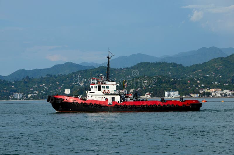 Κόκκινο ρυμουλκό στη θάλασσα με βουνοφόντο που ταξιδεύει στο λιμάνι Μπατούμι της Μαύρης Θάλασσας Γεωργία στοκ φωτογραφία Κόκκινο ρυμουλκό στη θάλασσα με βουνοφόντο που ταξιδεύει στο λιμάνι Μπατούμι της Μαύρης Θάλασσας Γεωργία στοκ φωτογραφία