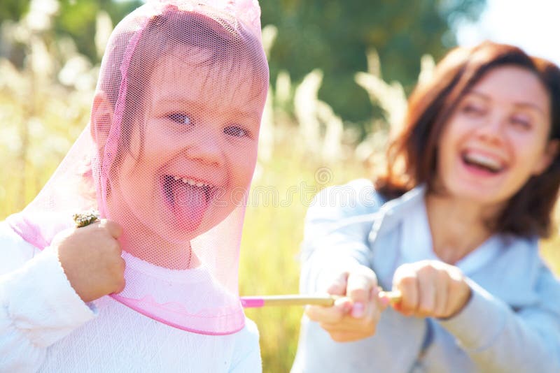 Young beautiful woman playing with her little cute girl in the meadow. Young beautiful woman playing with her little cute girl in the meadow