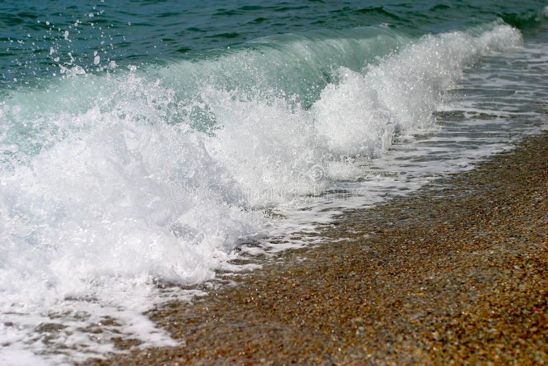 A wave breaking on a beach. A wave breaking on a beach