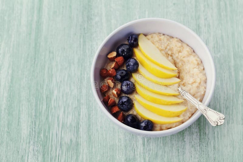 Κύπελλο oatmeal του κουάκερ με το μήλο, τα μούρα, το μέλι και το αμύγδαλο στον αγροτικό πίνακα, πρόγευμα διατροφής στοκ εικόνες