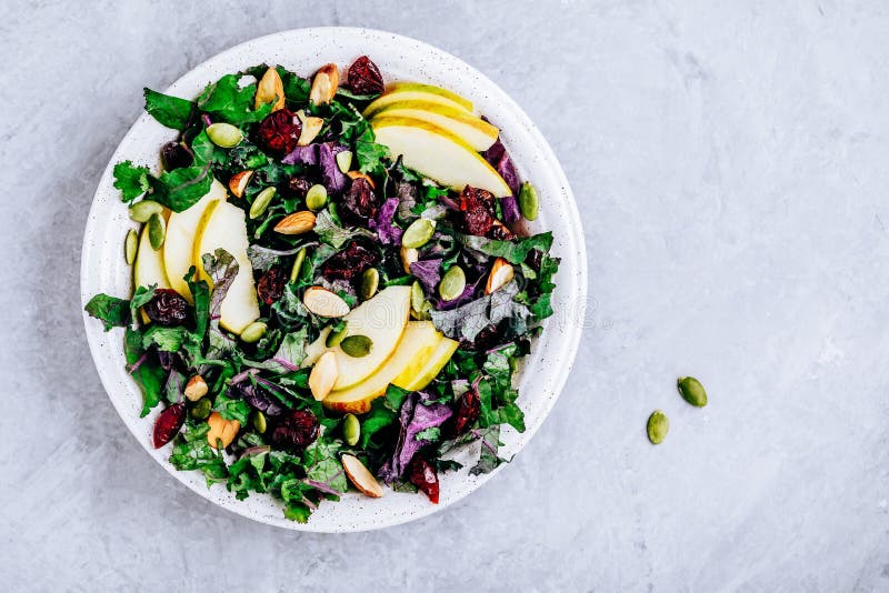 Apple Cranberry Kale Salad bowl with dry cranberries, almonds and pumpkin seeds. Fresh green vegan summer salad. Apple Cranberry Kale Salad bowl with dry cranberries, almonds and pumpkin seeds. Fresh green vegan summer salad
