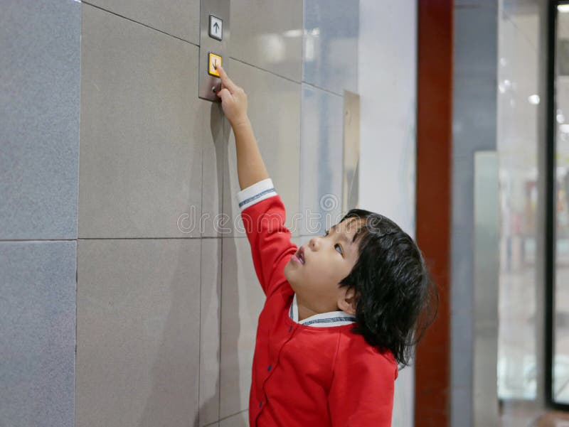 Little Asian baby girl 3 years old, reaching her hand out to try pushing the elevator button - children development by allowing them to help doing things in everyday life. Little Asian baby girl 3 years old, reaching her hand out to try pushing the elevator button - children development by allowing them to help doing things in everyday life