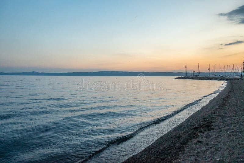 Λίμνη Bolsena, Λάτσιο, Ιταλία, στο ηλιοβασίλεμα με τα δέντρα βαρκών και τον κόκκινο ουρανό στοκ φωτογραφίες Λίμνη Bolsena, Λάτσιο, Ιταλία, στο ηλιοβασίλεμα με τα δέντρα βαρκών και τον κόκκινο ουρανό στοκ φωτογραφίες
