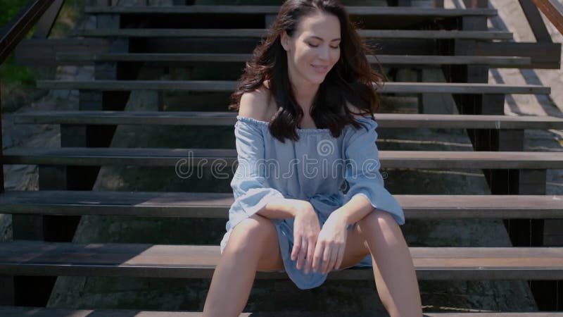 Λατρευτή συνεδρίαση γυναικών brunette στα σκαλοπάτια σε υπαίθριο φιλμ μικρού μήκους