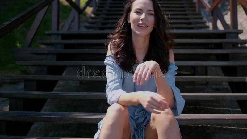 Λατρευτή συνεδρίαση γυναικών brunette στα σκαλοπάτια σε υπαίθριο φιλμ μικρού μήκους