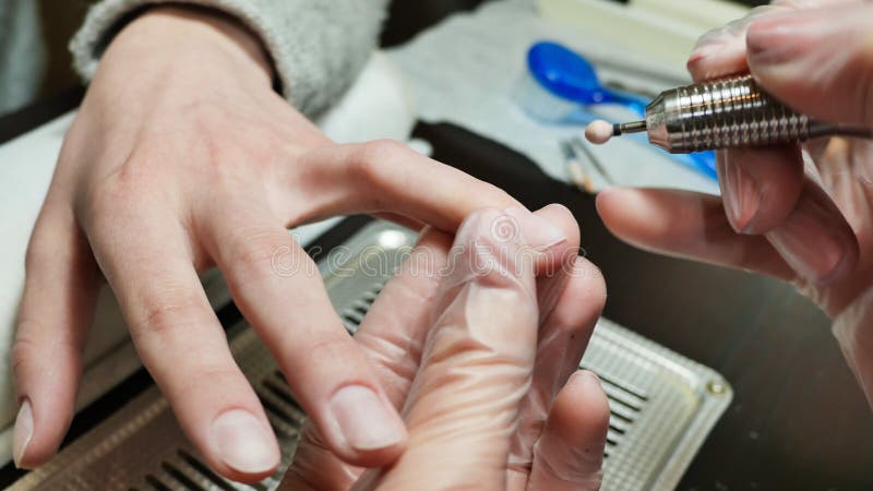 Λείανση μιας επιδερμίδας και δευτερευόντων κυλίνδρων Χέρια γυναικών ` s στις διαδικασίες μανικιούρ στοκ εικόνα με δικαίωμα ελεύθερης χρήσης Λείανση μιας επιδερμίδας και δευτερευόντων κυλίνδρων Χέρια γυναικών ` s στις διαδικασίες μανικιούρ στοκ εικόνα με δικαίωμα ελεύθερης χρήσης