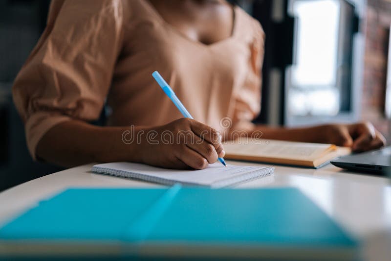 λεπτομέρεια κοφτερή φωτογραφία μη αναγνωρίσιμης αμερικανίδας φοιτήτριας που χρησιμοποιεί φορητό υπολογιστή και χάρτινες σημειώσεις στοκ φωτογραφίες