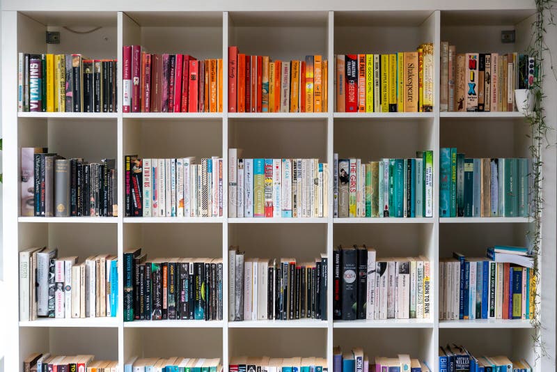 Brighton, England - August 03 2019: White wooden bookcase filled with books in a UK home setting. Brighton, England - August 03 2019: White wooden bookcase filled with books in a UK home setting