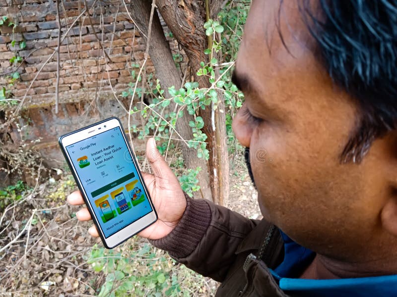 Instant adhaar loan application software presented on smart phone screen at village area by indian villager in India Dec 2019. Instant adhaar loan application software presented on smart phone screen at village area by indian villager in India Dec 2019