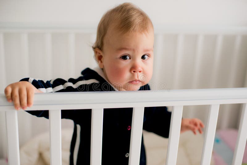 The baby cries and calls mom from a bed. The baby cries and calls mom from a bed