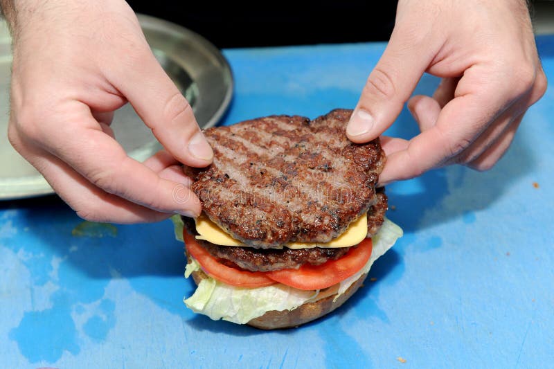 Μάγειρας που προσθέτει burger στα έτοιμα κουλούρια για το χάμπουργκερ Προετοιμασία και κατασκευή του χάμπουργκερ στοκ φωτογραφία με δικαίωμα ελεύθερης χρήσης Μάγειρας που προσθέτει burger στα έτοιμα κουλούρια για το χάμπουργκερ Προετοιμασία και κατασκευή του χάμπουργκερ στοκ φωτογραφία με δικαίωμα ελεύθερης χρήσης