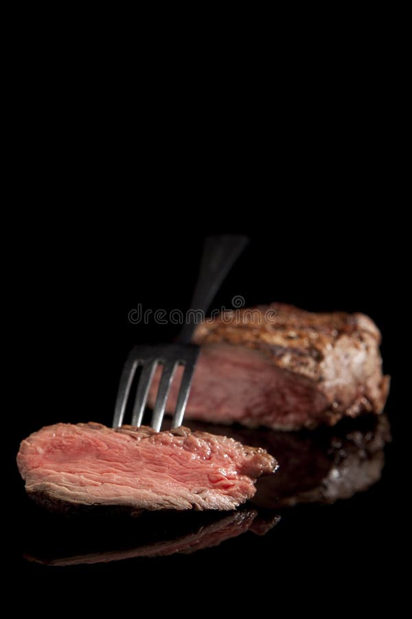 Delicious beef steak with fork on black background. Delicious beef steak with fork on black background