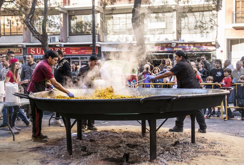 VALENCIA, SPAIN - NOVEMBER 6, 2016.Cooking a giant Paella, traditional Valencian food, on Plaza del Mercado at 100 years since the founding of the central market, Valencia, Spain. VALENCIA, SPAIN - NOVEMBER 6, 2016.Cooking a giant Paella, traditional Valencian food, on Plaza del Mercado at 100 years since the founding of the central market, Valencia, Spain.