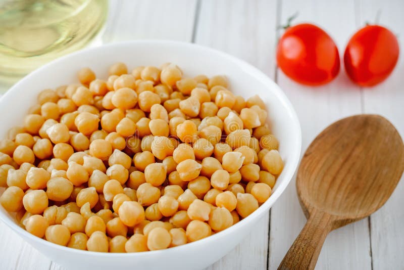 Μαγειρευμένα chickpeas με ένα πιάτο, τις ντομάτες και το ελαιόλαδο σε έναν ξύλινο πίνακα στοκ φωτογραφία με δικαίωμα ελεύθερης χρήσης