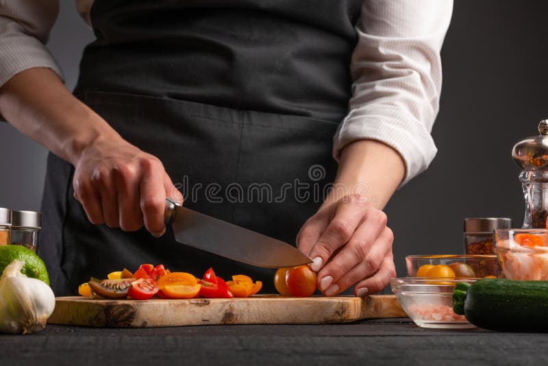 μαγειρική λαχανικά με γαρίδες. σεφ τεμαχίζει ντομάτες κεράσι σε γκρι φόντο με γαρίδες. θαλασσινά στοκ εικόνα