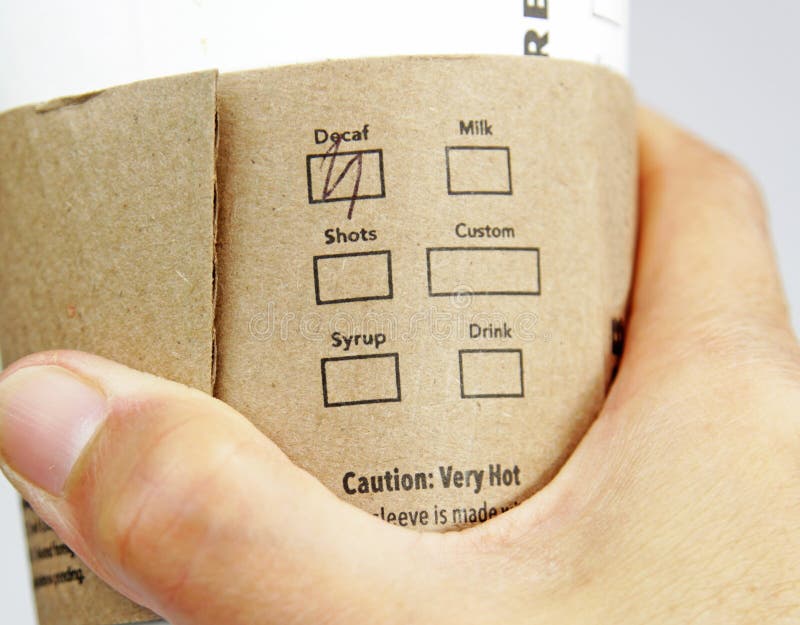 Hand holding a commercial cup with earth friendly safety sleeve marked with the decaf selection. Hand holding a commercial cup with earth friendly safety sleeve marked with the decaf selection
