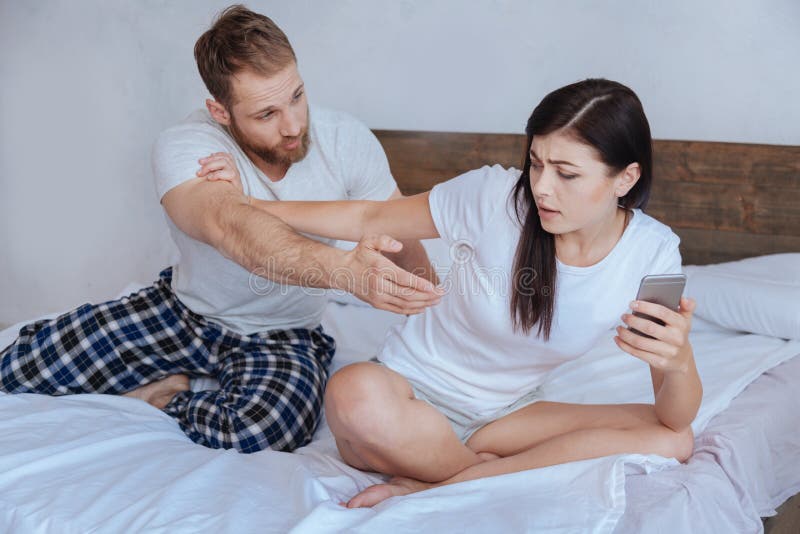 Ματαιωμένος νεαρός άνδρας που παίρνει το smartphone φίλων του στοκ εικόνα Ματαιωμένος νεαρός άνδρας που παίρνει το smartphone φίλων του στοκ εικόνα