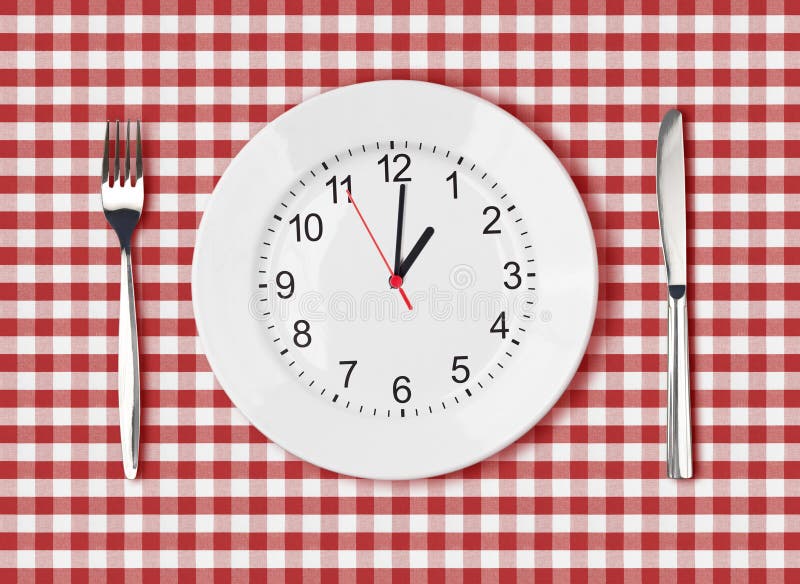 Knife, white plate with clock face and fork on red picnic table cloth. Knife, white plate with clock face and fork on red picnic table cloth