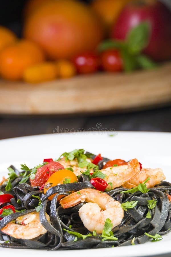 Μαύρα ζυμαρικά Fettuccine μελανιού καλαμαριών με τις ντομάτες κερασιών γαρίδων ή γαρίδων, το μαϊντανό, το τσίλι στο κρασί και τη στοκ φωτογραφίες Μαύρα ζυμαρικά Fettuccine μελανιού καλαμαριών με τις ντομάτες κερασιών γαρίδων ή γαρίδων, το μαϊντανό, το τσίλι στο κρασί και τη στοκ φωτογραφίες