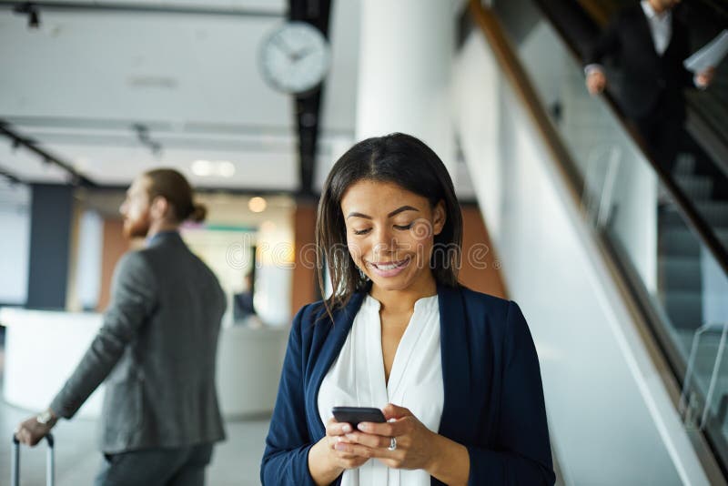 Μαύρο γυναικείο texting μήνυμα χαμόγελου στον αερολιμένα στοκ εικόνες Μαύρο γυναικείο texting μήνυμα χαμόγελου στον αερολιμένα στοκ εικόνες
